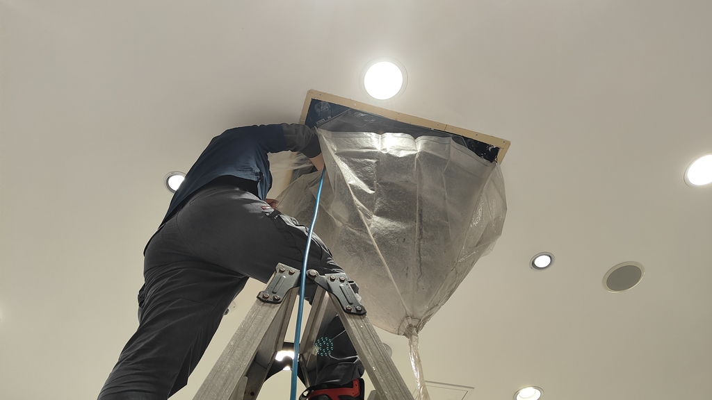 天井カセット形業務用エアコンを養生して洗浄している自社施工の作業風景
